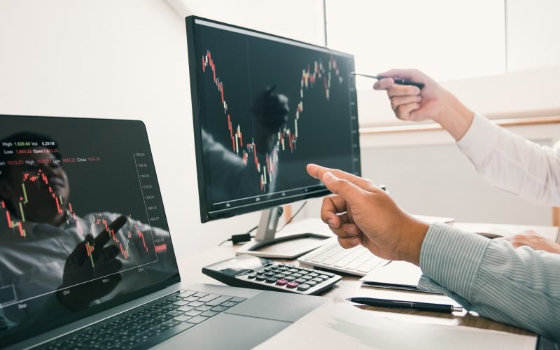 Two business stock brokers stress and looking at monitors displaying financial Two business stock brokers stress and looking at monitors displaying financial